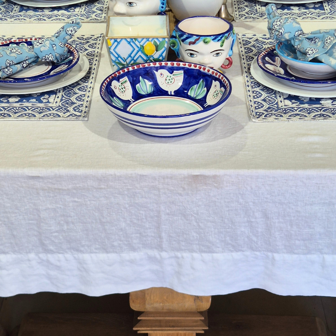 Decorative table setting with blue and white ceramic bowls and plates on a white tablecloth.