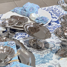 Silver platters and bowls on a blue and white patterned tablecloth.