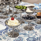 Silver dessert dishes with various desserts on a patterned tablecloth