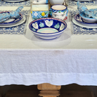 Decorative table setting with blue and white ceramic bowls and plates on a white tablecloth.